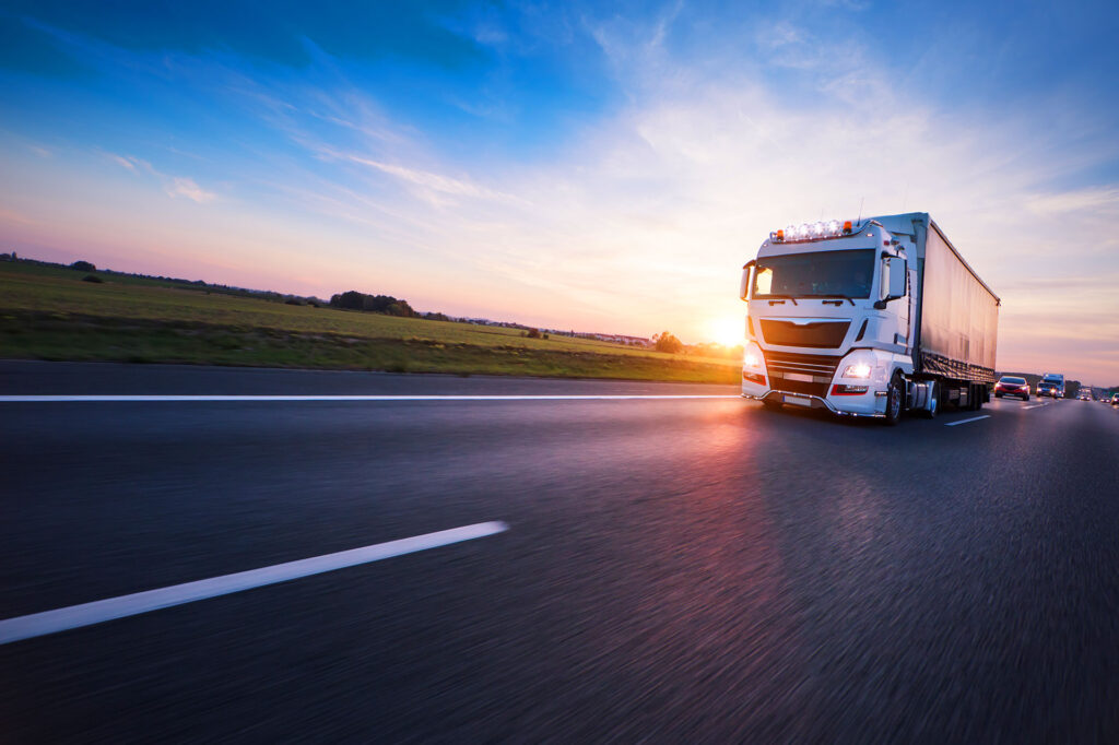 White semi truck driving on highway at sunset